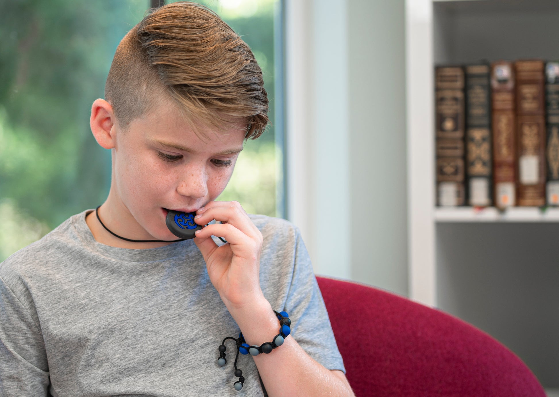 Boy chews on Munchables Ninja Star Chew Necklace. Also wears boys chew bracelet in navy camo.