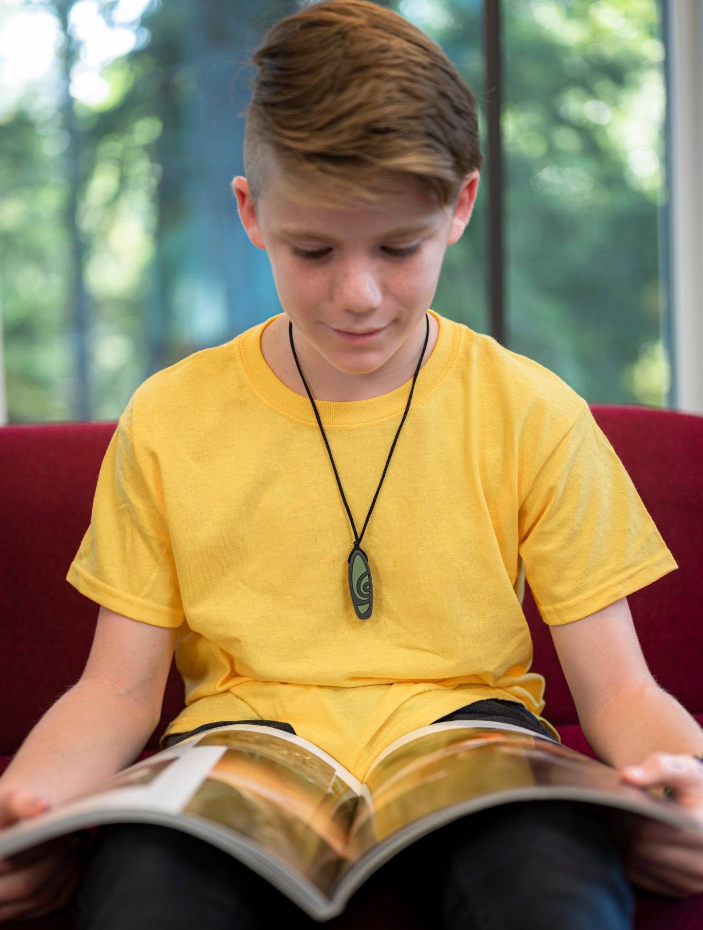 Boy wears Munchables Surfboard Chewelry while reading