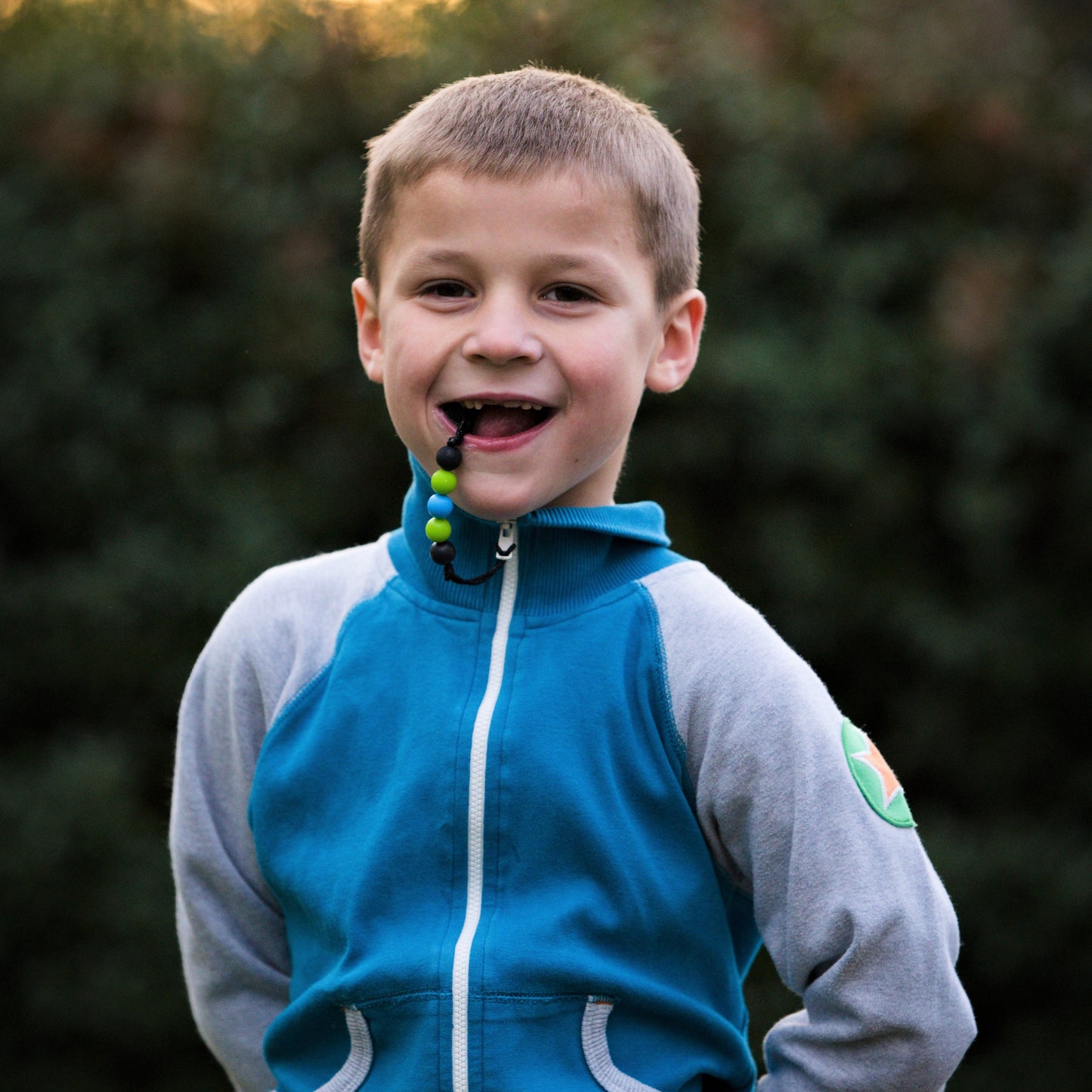 Boy bites chewable zipper pull attached to his jacket.