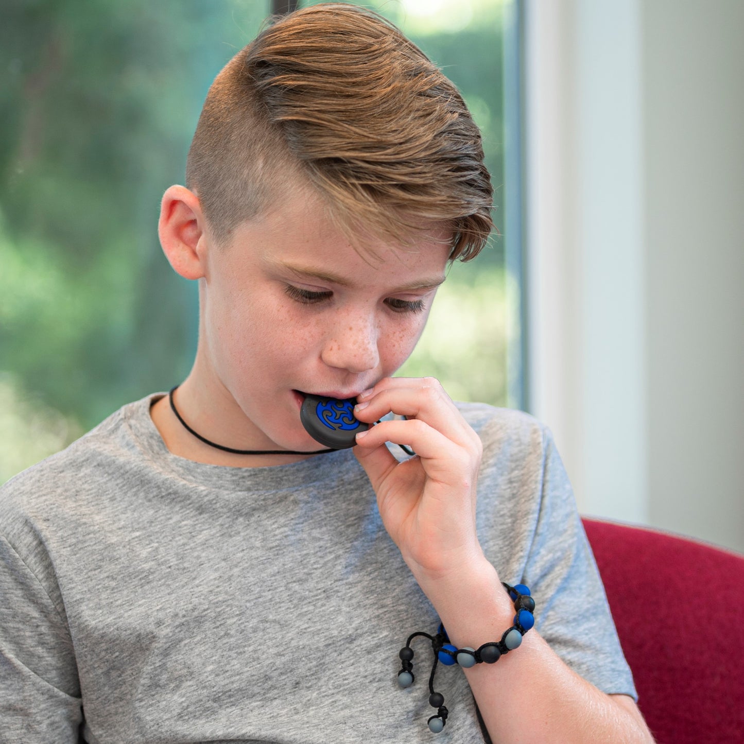 Boy wearing navy camo chew bracelet and chewing on navy blue ninja star chewelry.