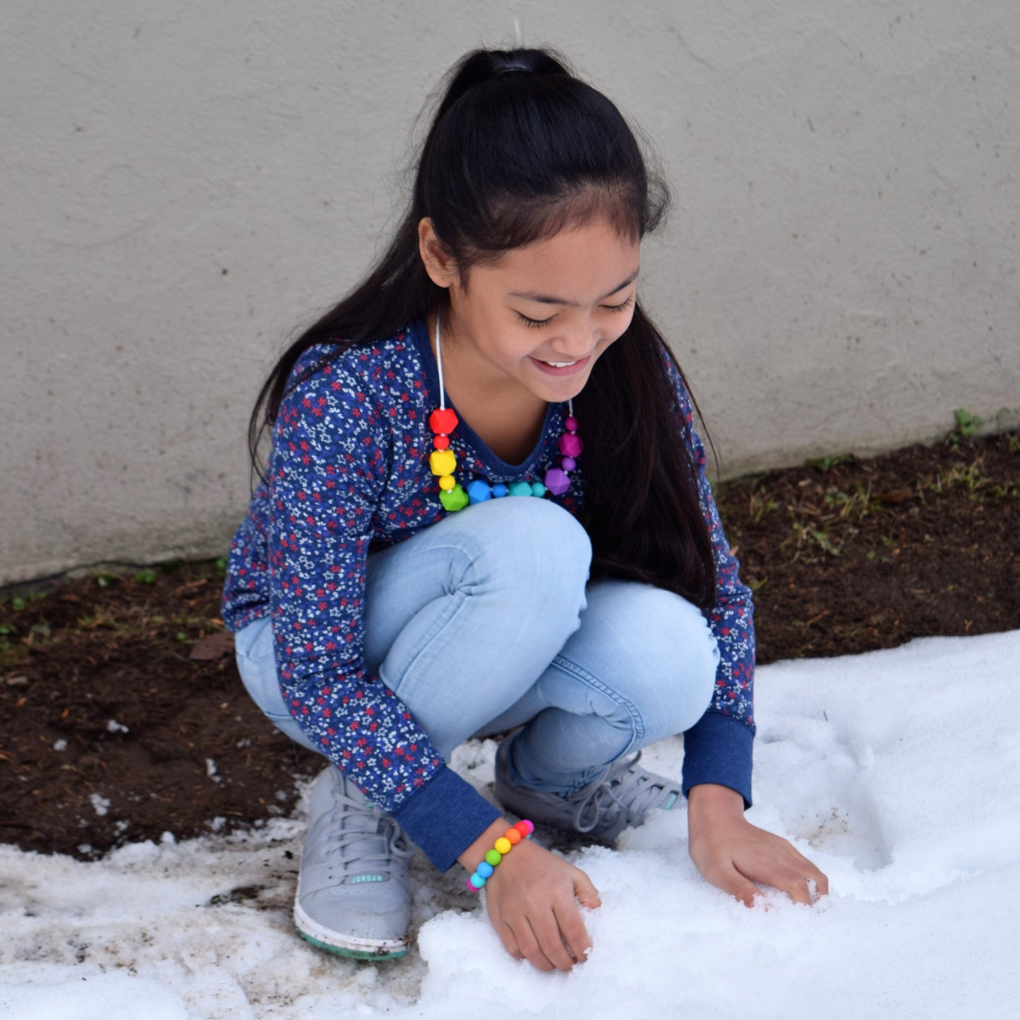 Munchables Rainbow Chew Necklace worn by a girl playing in the snow.