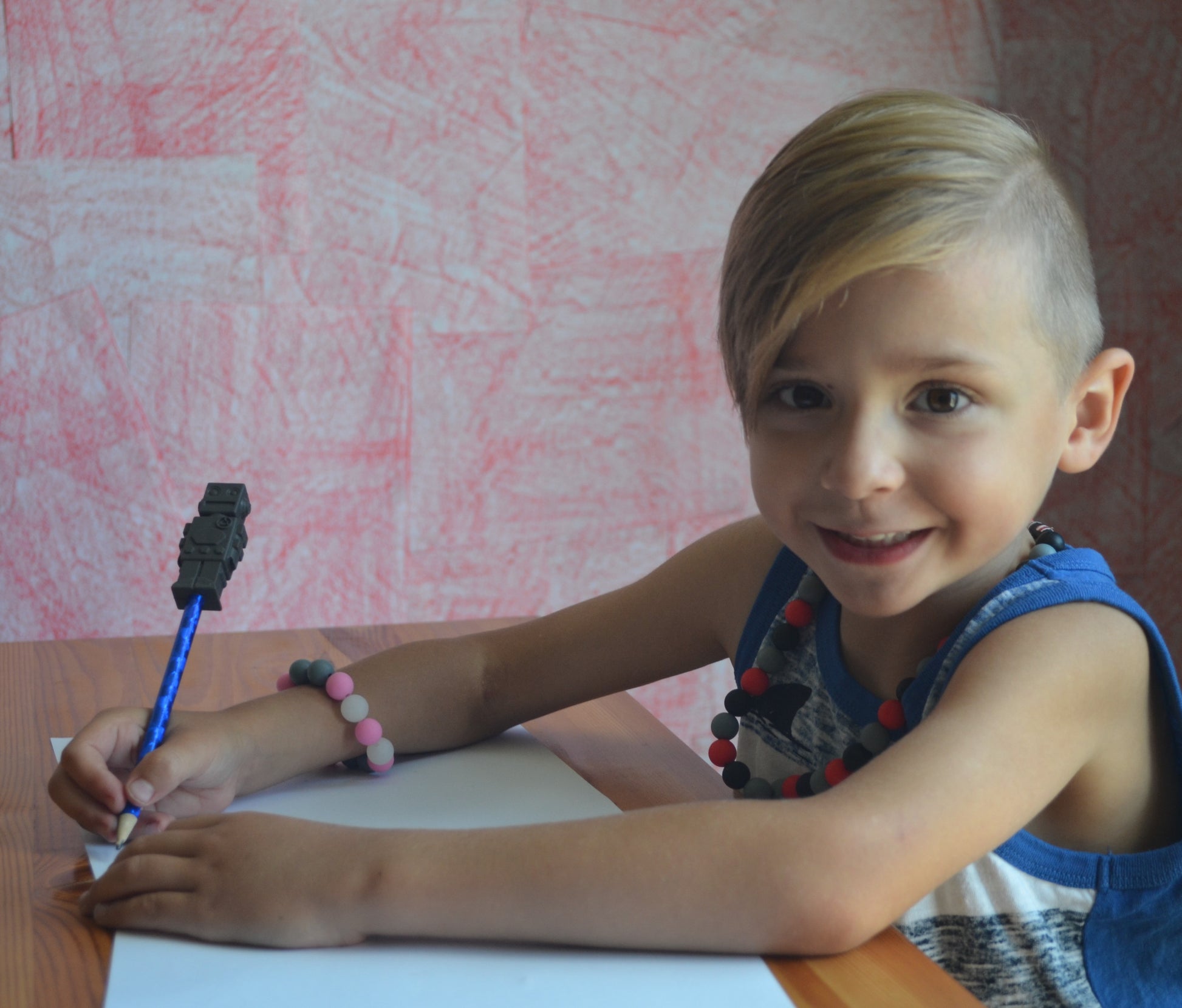 Boy uses charcoal robot chewy pencil topper on pencil.